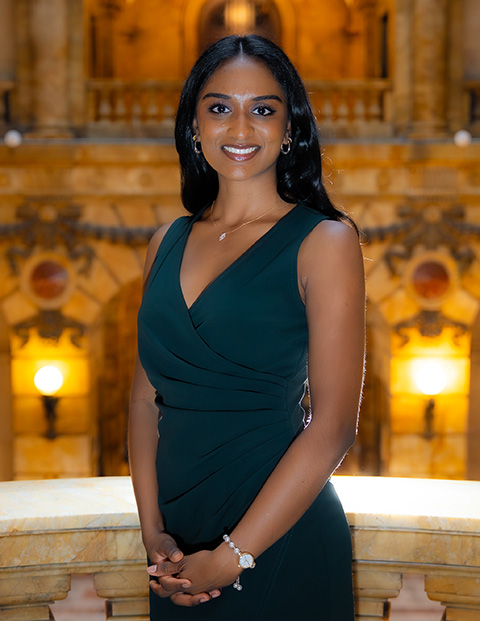 Person smiling, wearing a dark green dress.