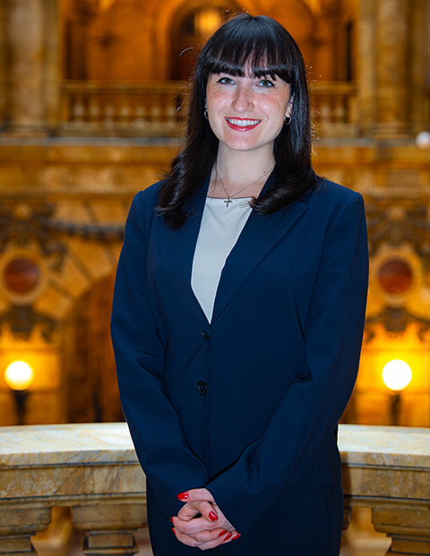 Person smiling, wearing a royal blue blazer and red nail polish.