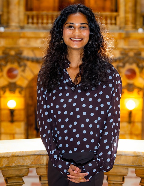 Person smiling, wearing a brown shirt with blue polka dots.