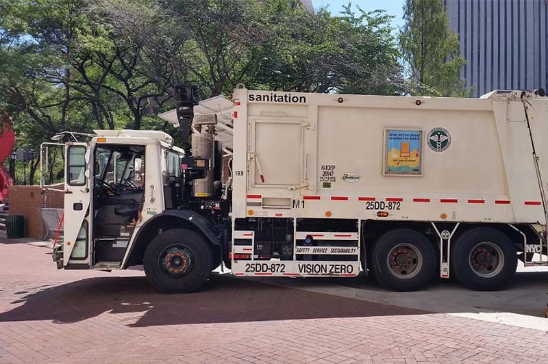 Sanitation truck with Vision Zero side guard in the back of One Centre Street