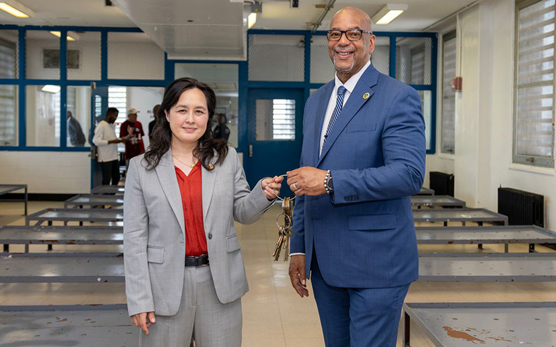 Department of Citywide Administrative Services (DCAS) Commissioner Yume Kitasei accepts keys from Department of Correction (DOC) Commissioner Stanley Richards to mark the transfer of Rikers facilities to DCAS.