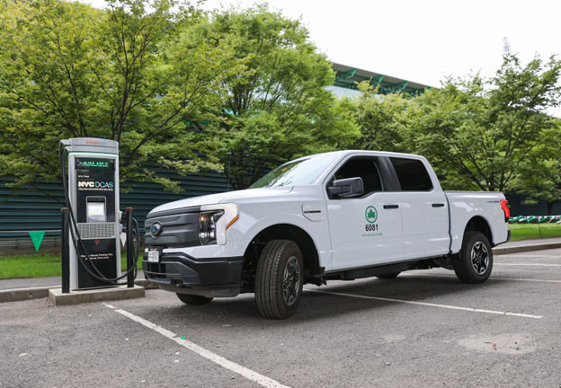 White Parks Dept. pick-up truck using a charging station in a park like setting.