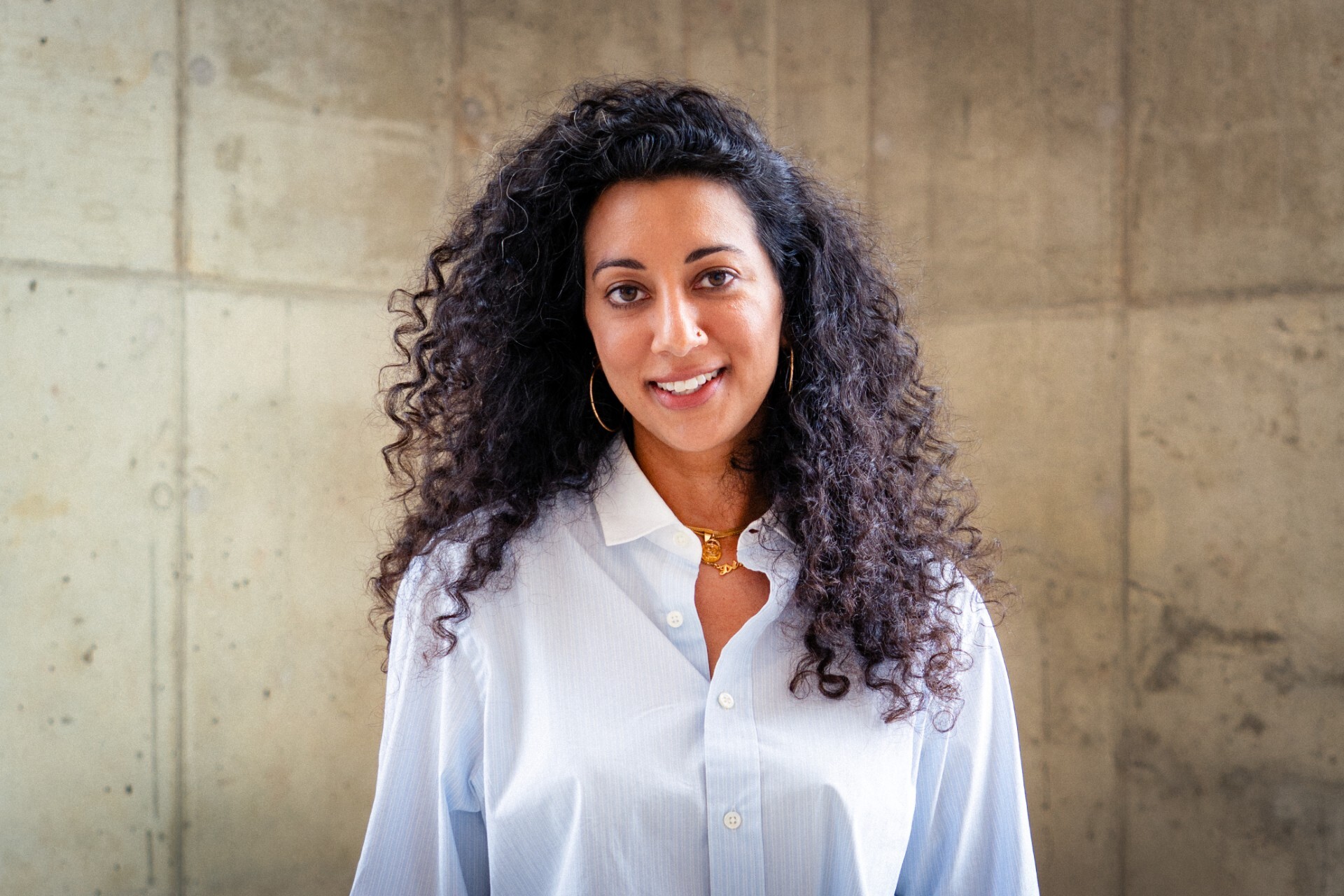 Diya Vij wears a light blue shirt; her long curly hair falls over her shoulders.