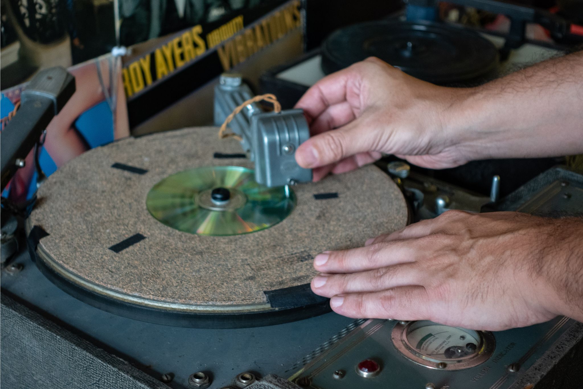 Hands positioning a CD on a record turntable