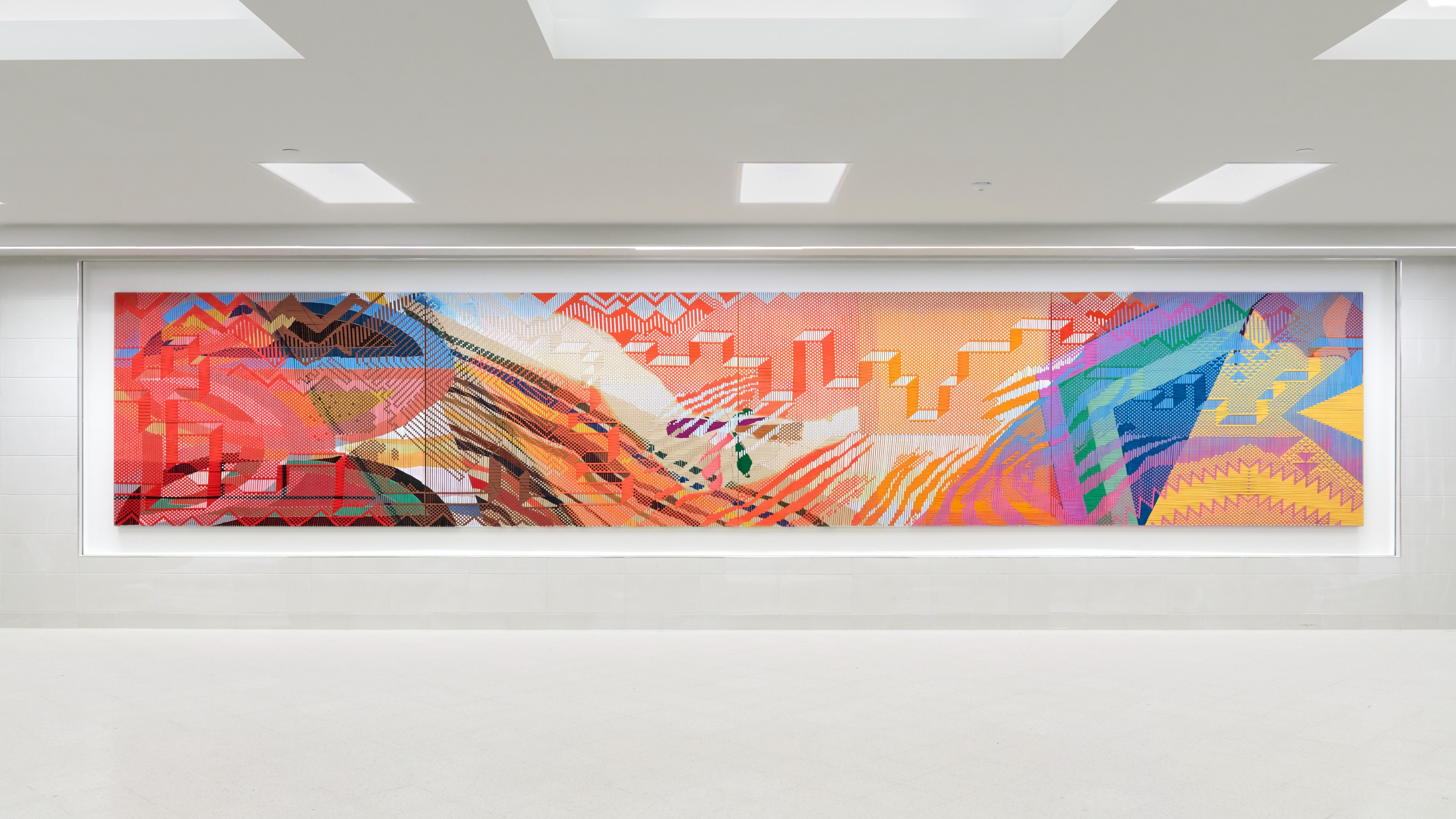 A woven mural with warm colors and geometric shapes in the school hallway.