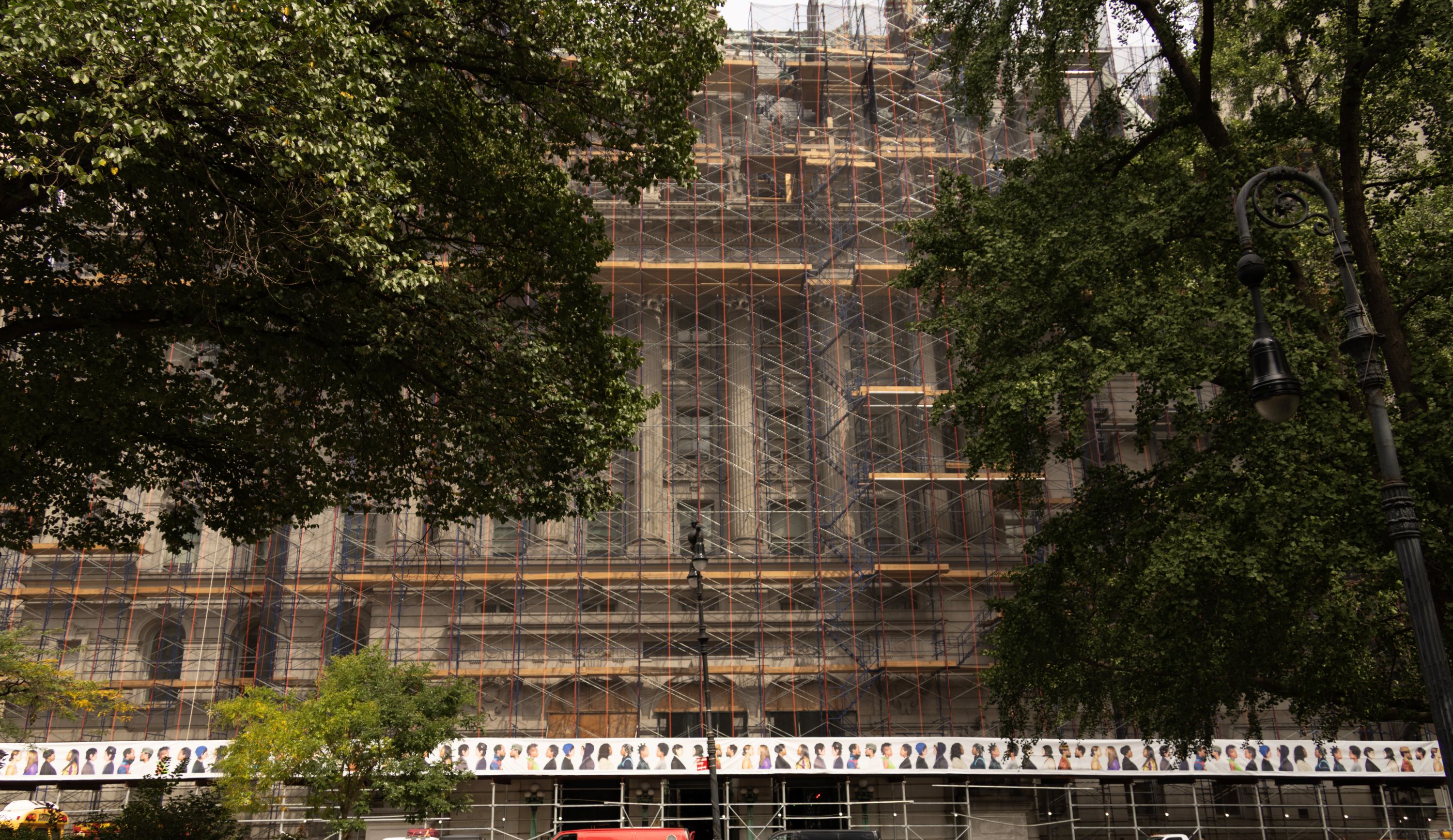 On the sidewalk shed of 31 Chambers, is an installation of photos of people