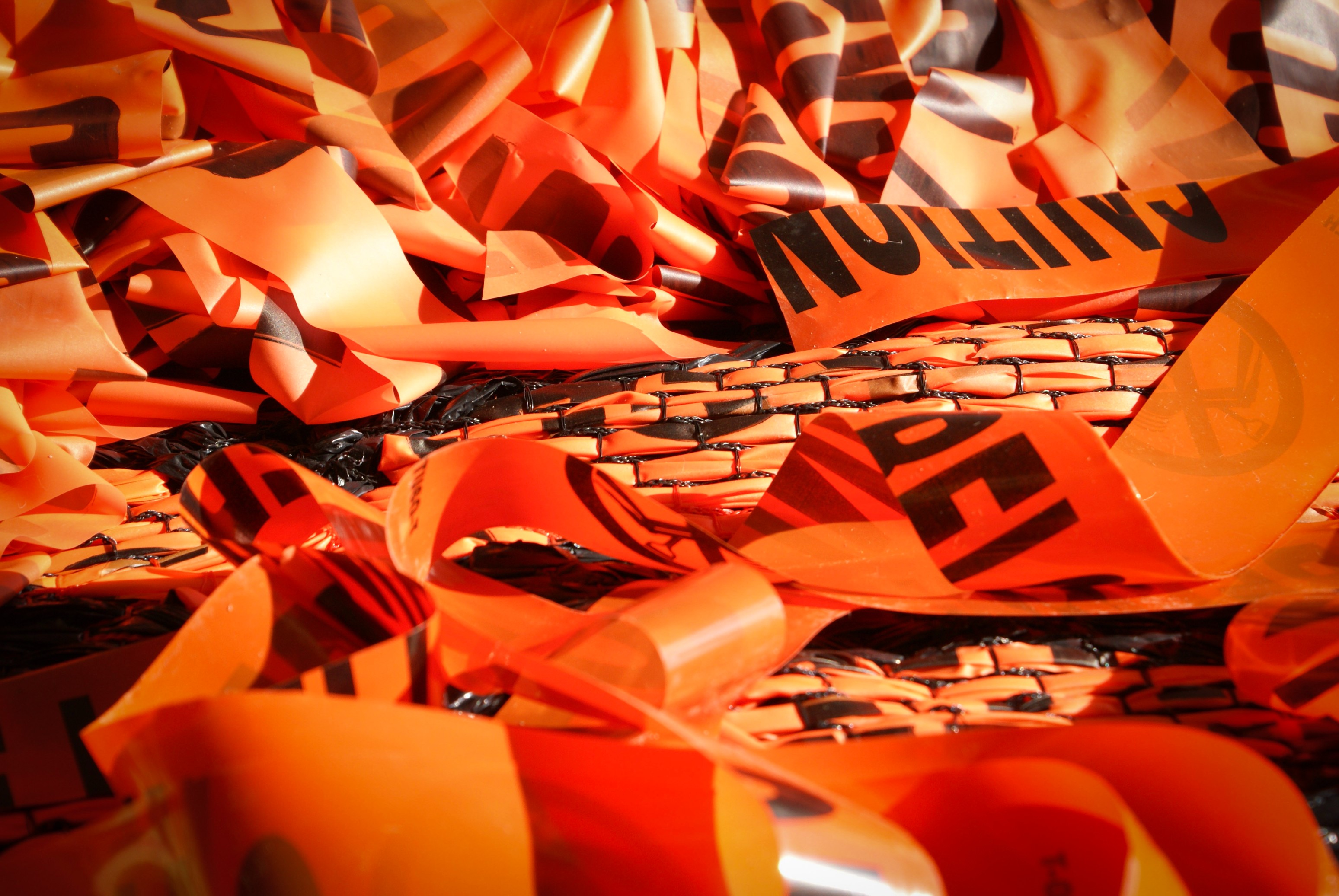 A closeup of bright orange woven caution tape in Borinquen Gallo's work.