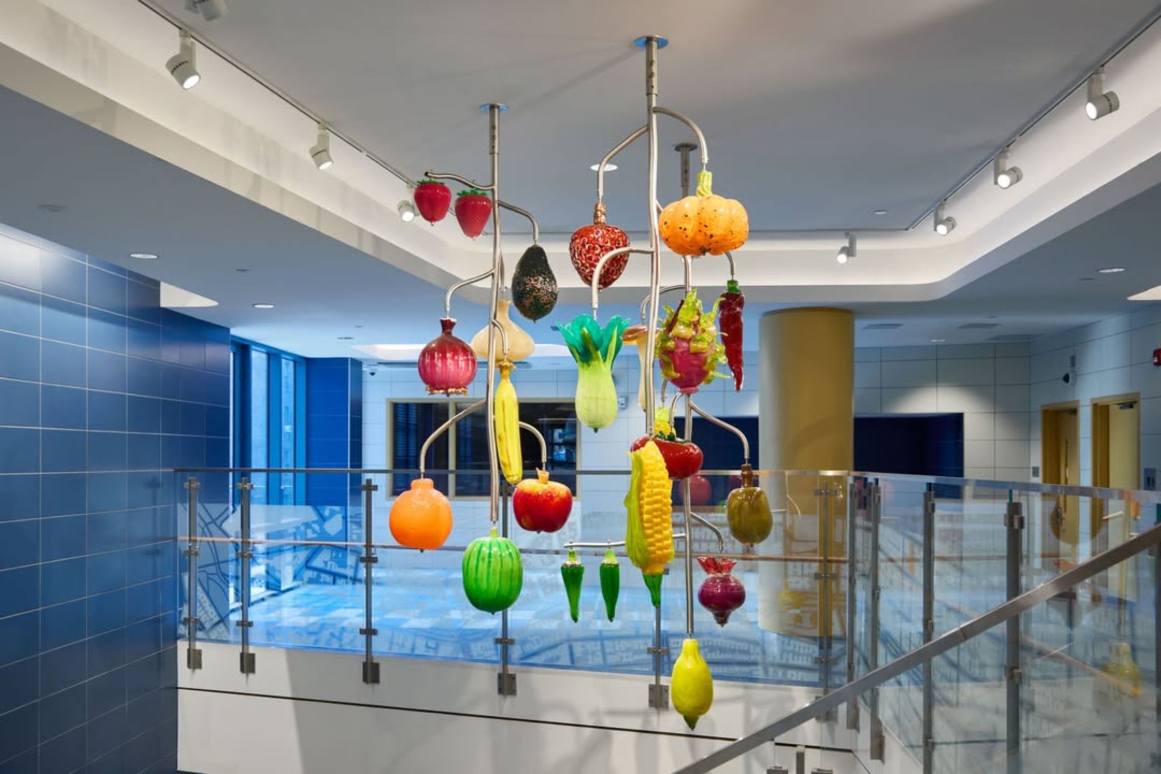 A colorful glass installation of fruits and vegetables hangs from the ceiling.