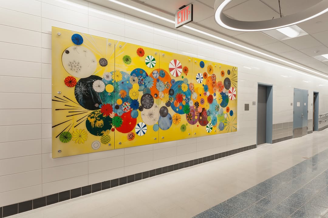 A bright mural at PS 26Q with a yellow background and colorful circular shapes.