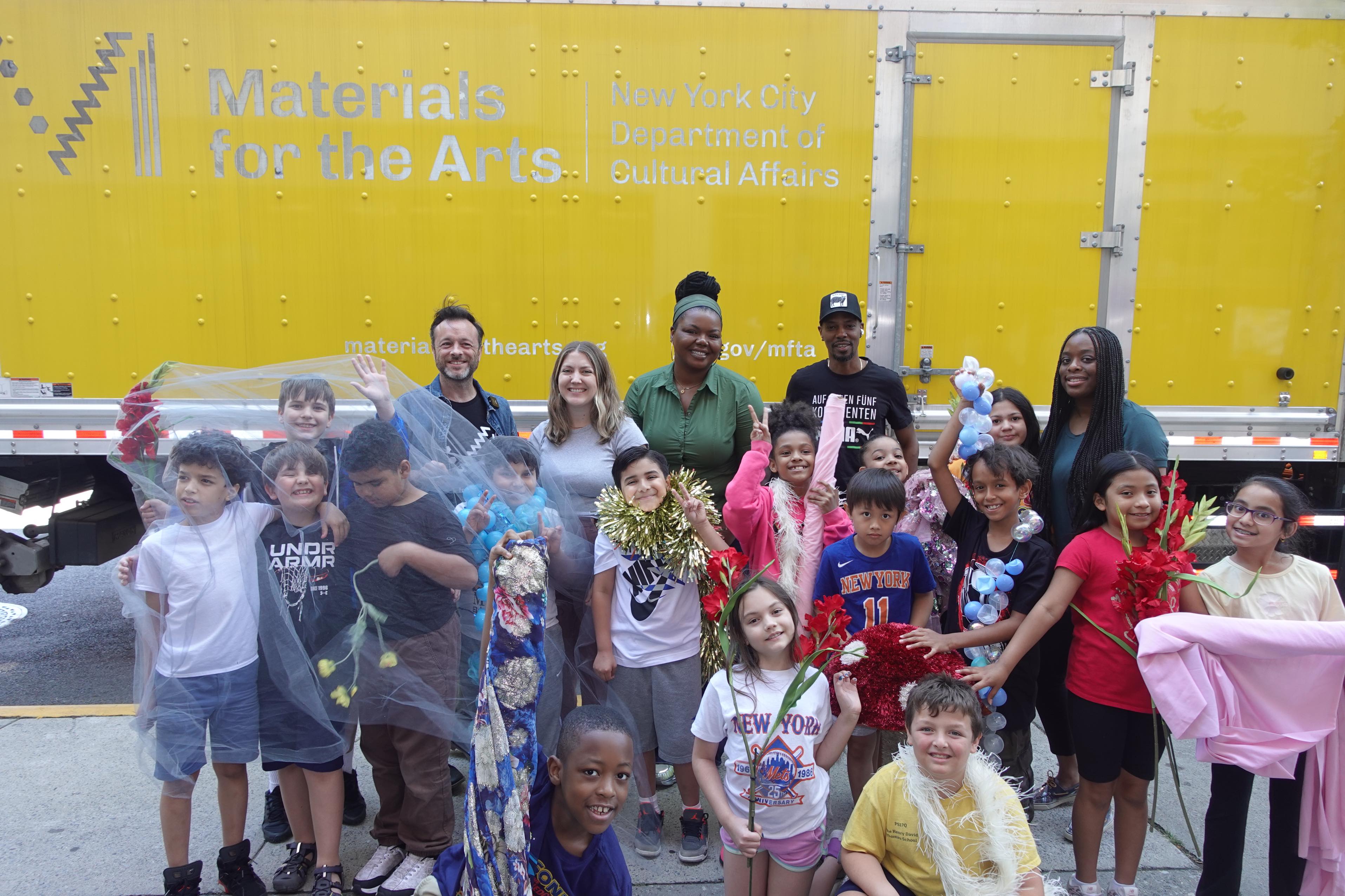MFTA staff, students, and teachers smile in front of MFTA's yellow truck.