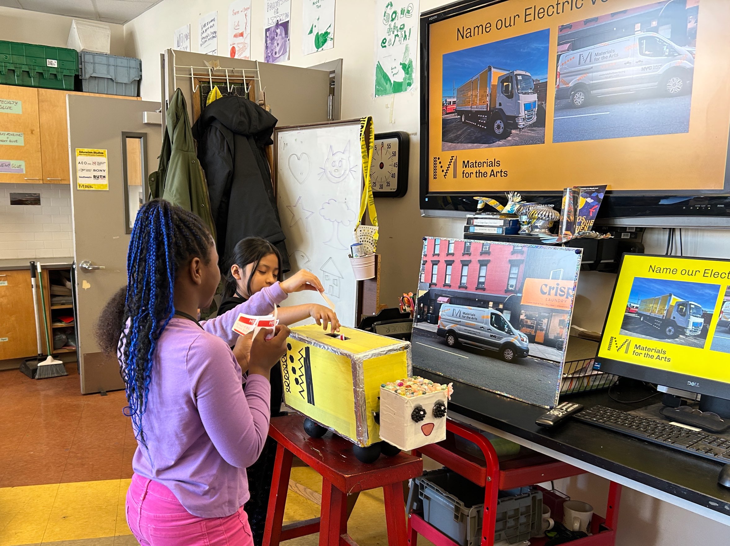 Students place name suggestions into a papier-mâché truck in the classroom.