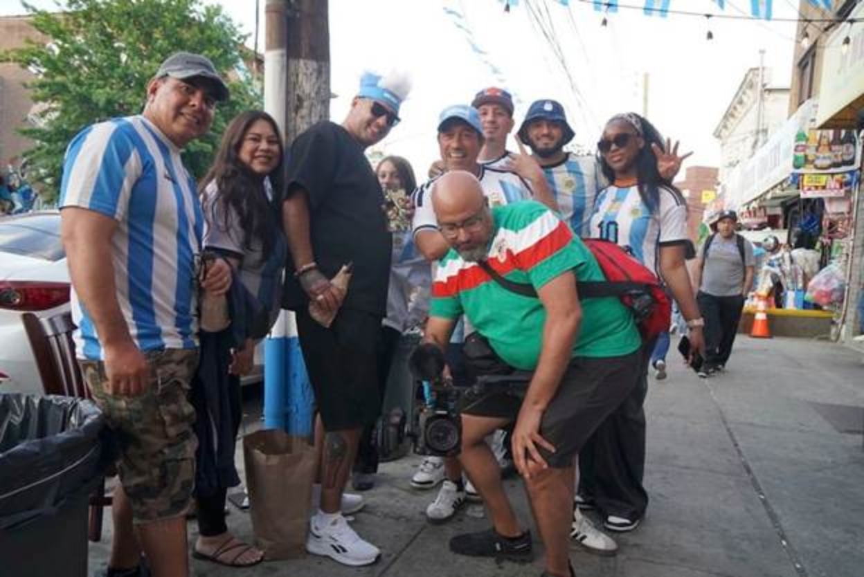 A photo of Michael Premo holding up a camera with a group of Argentina fans.