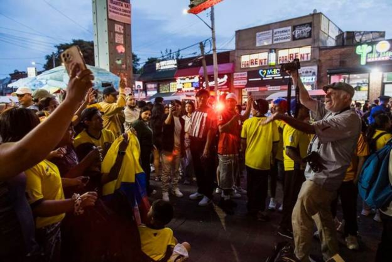 A photo of a person taking a photo of a World Cup watch party outside.