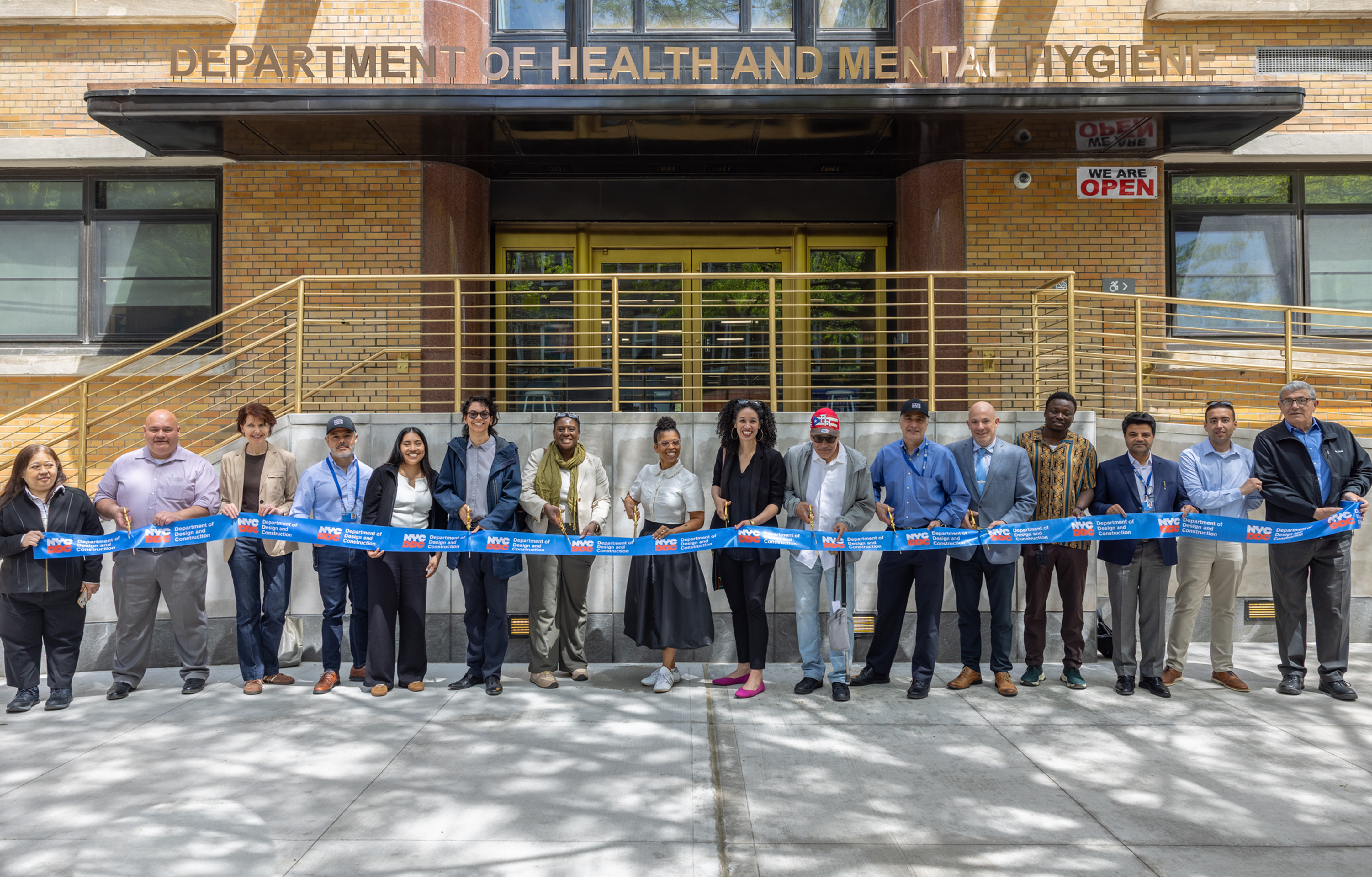 group photo of officials holding ceremonial ribbon and scissors in front of the health center
                                           