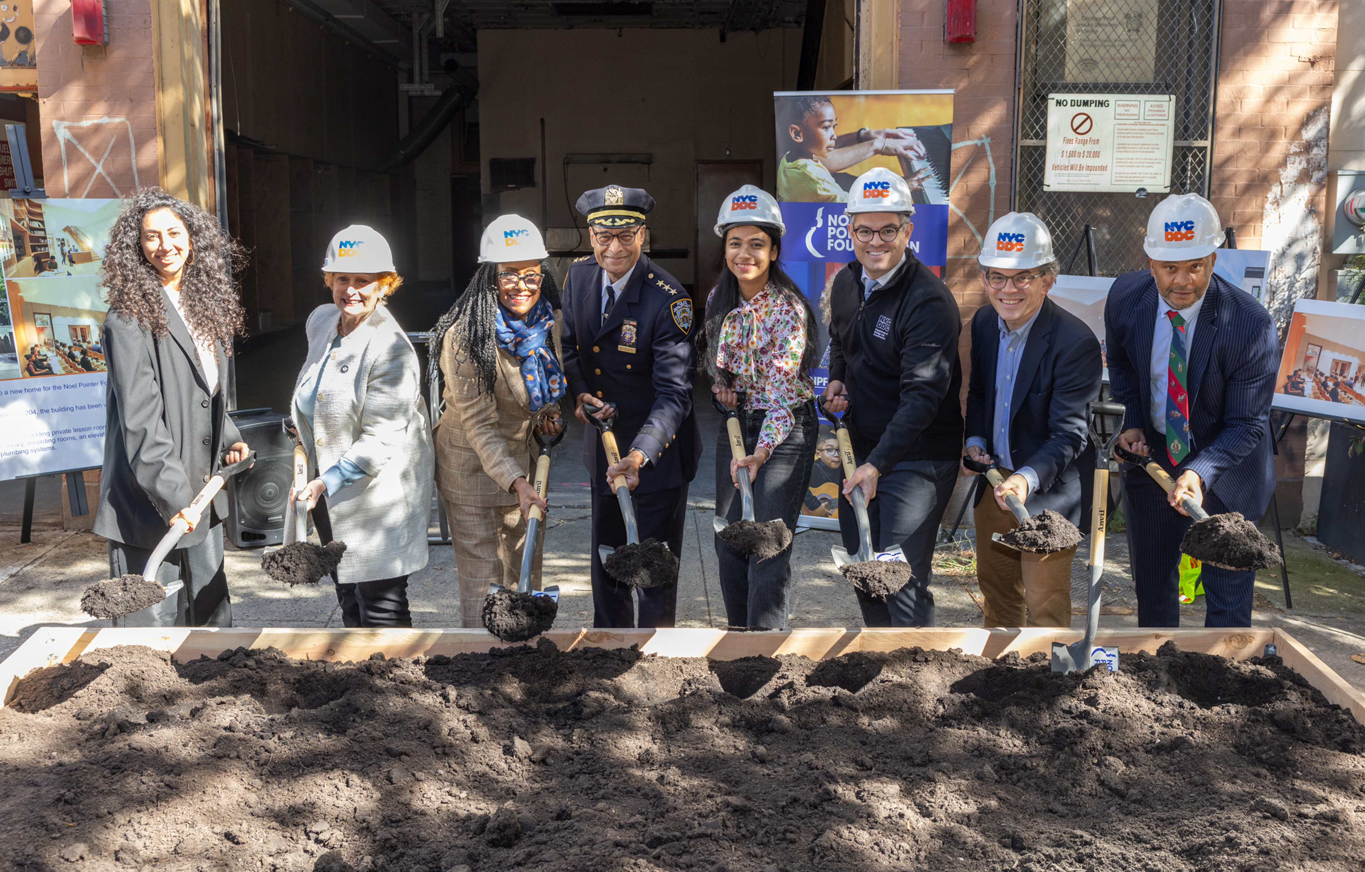 Elected, City officials stand holding shovels to break ground 
                                           