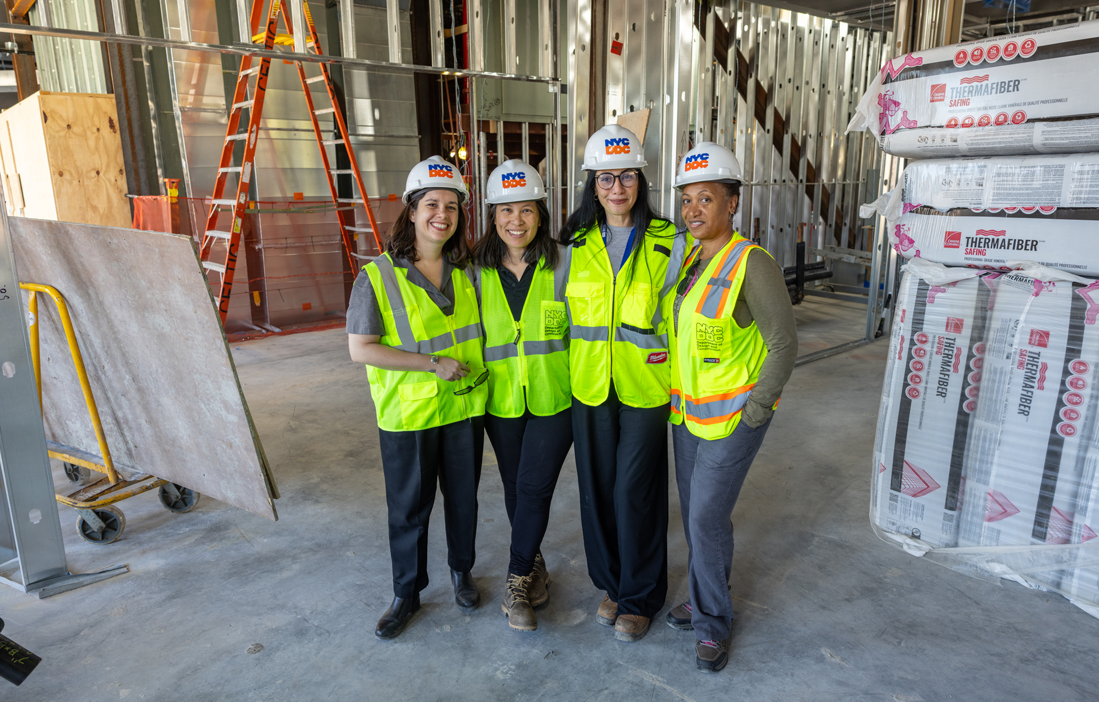A group photo of four women on a construction site wearing construction helmets and other gear
                                           