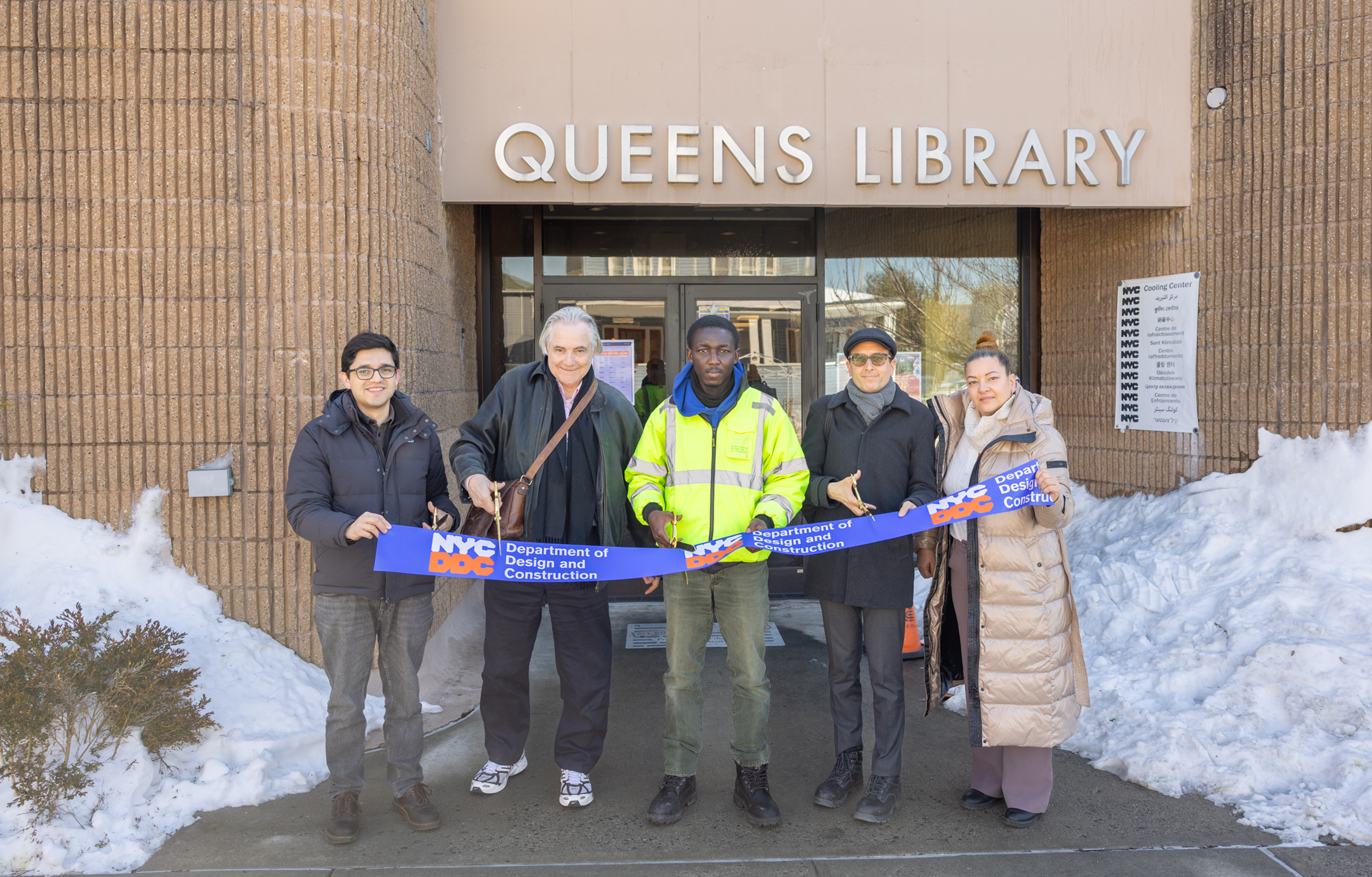 DDC employees hold up ceremonial ribbon and scissors in front of the Seaside Library
                                           