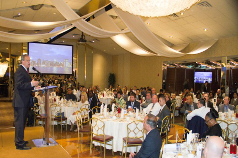 A speaker talks to a room of people sitting at tables.