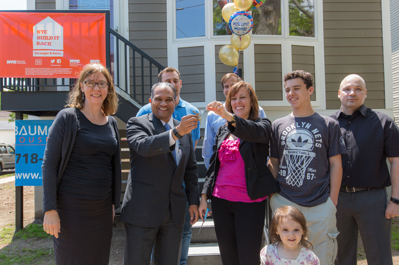 DDC Commissioner stands with a Staten Island family in front of their newly rennovated home.