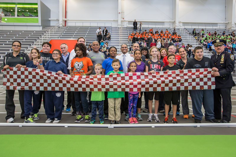 Officials and children preparing to cut a ribbon for the Athletic Complex.