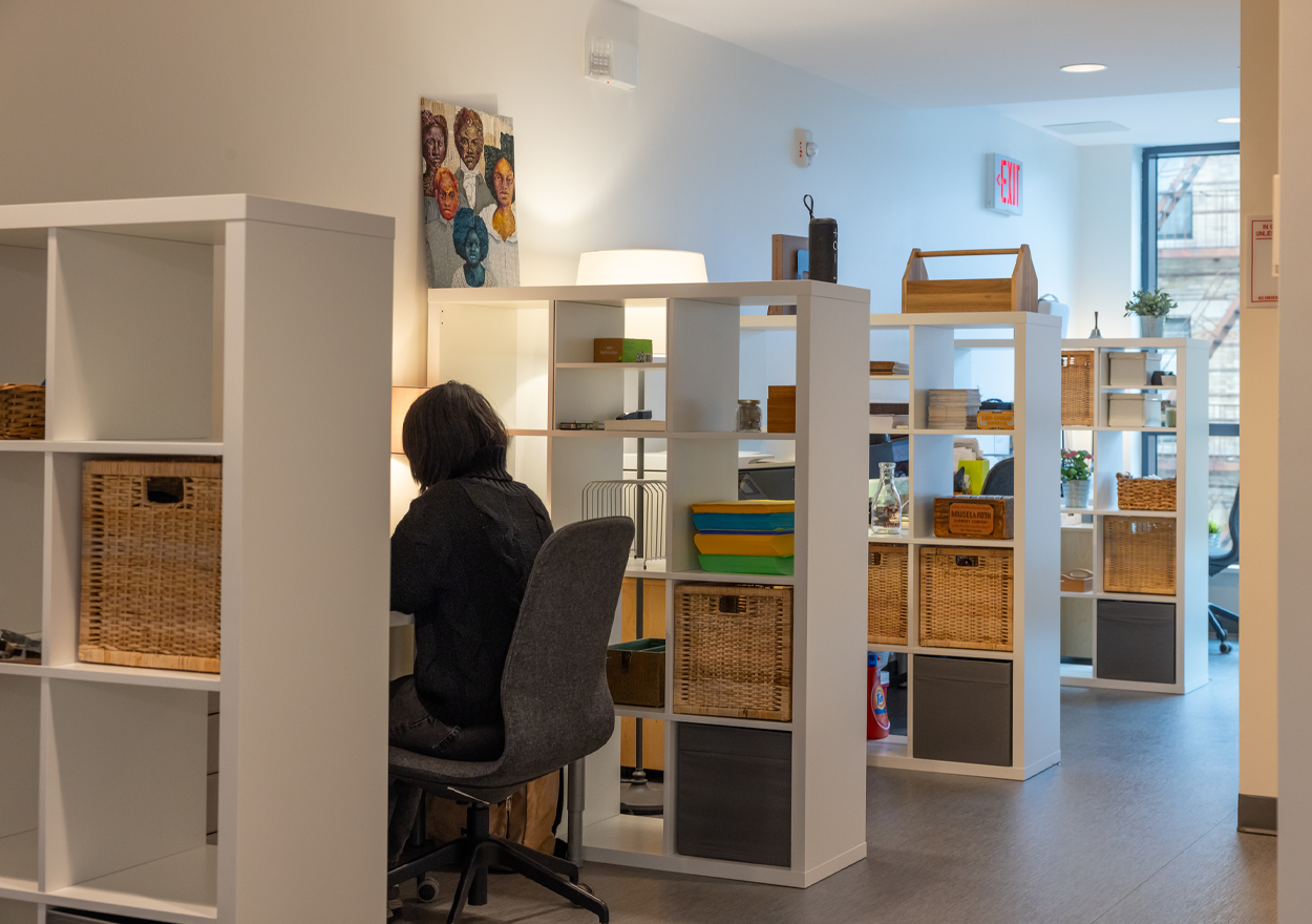 a person sits at a workstation surrounded by bookshelves