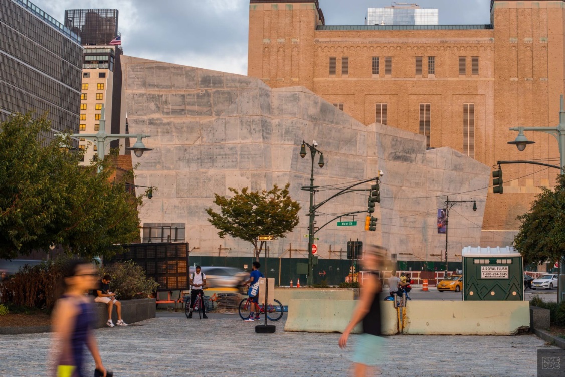 Pedestrians walk by the West Side Highway. In the background stands the Salt Shed.