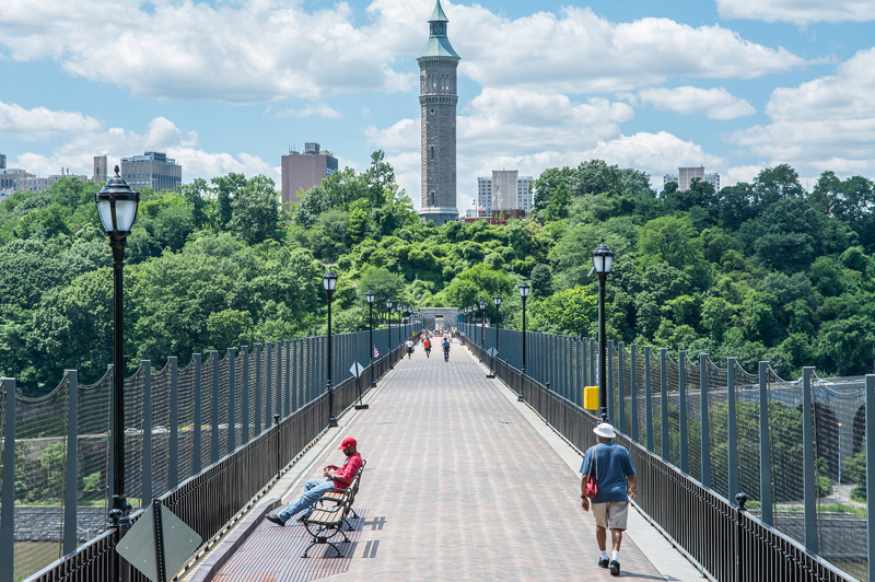 A view across the High Bridge. Pedestrians stroll and sit on benches.