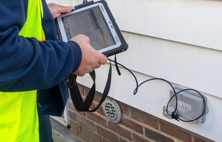 A technician connects to an AMR device during the installation process next to a home. 
                                           