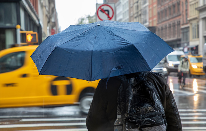 Person with an umbrella crossing the street in a rain storm.
                                           