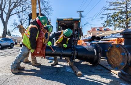 workers holding large pipe