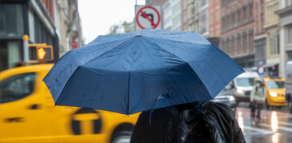 Person with an umbrella crossing the street in a rain storm.