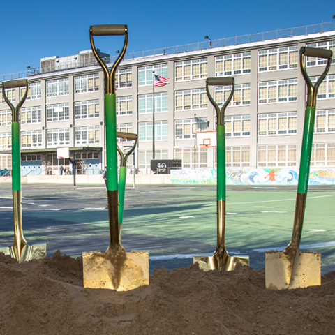 Stakeholders with shovels gather in front of a sign