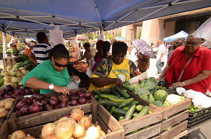 Older adults at a farmers market looking for fruits and vegetables to purchase. 