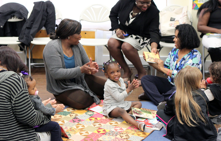Circle of women playing with a happy toddler.