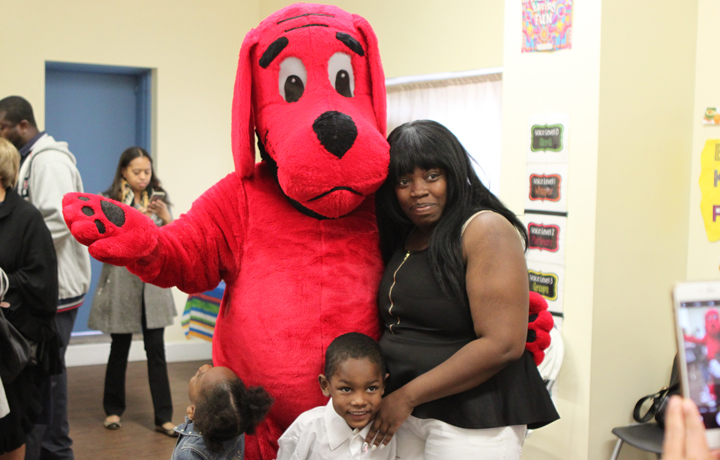 Mother and children standing next to red large dog mascot