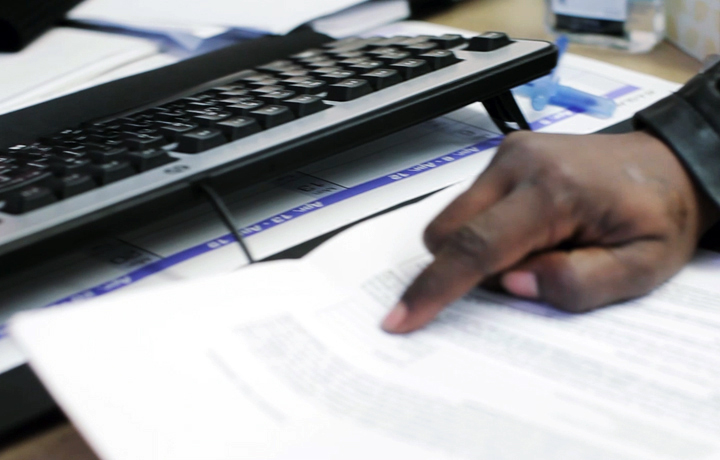 Man pointing at paperwork in front of a computer keyboard