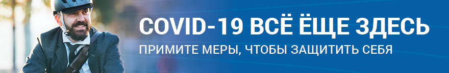 Фото сидящего в автобусе человека в маске. Текст: COVID-19 все еще здесь. Примите меры, чтобы защитить себя.