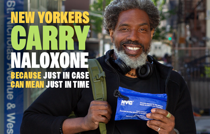 Man smiles while holding a naloxone kit. Text reads: New Yorkers carry naloxone because just in case can mean just in time.
                                           