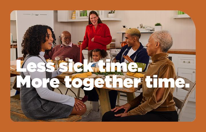 A happy family is gathered around a dinner table, enjoying each other's company. Text reads: Less sick time. More together time.
                                           