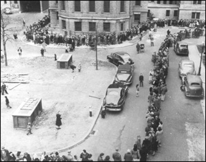 A black and white photo of New Yorkers reciving smallpox vaccines in 1947. A long line of people fills the street.