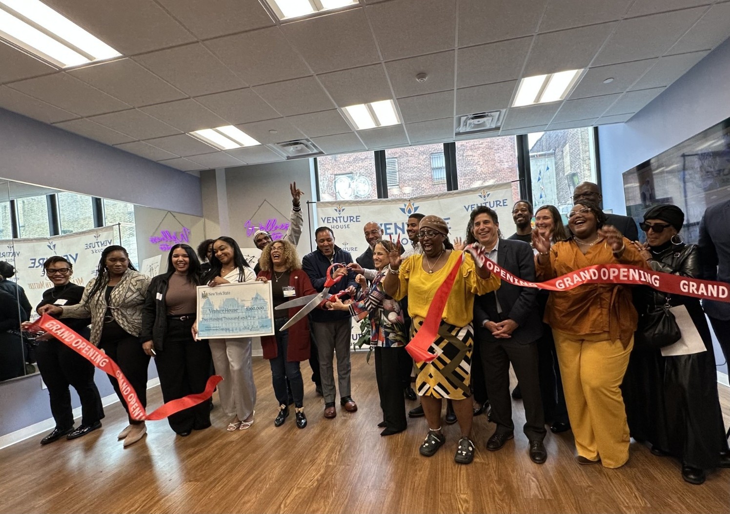 Diverse group of adults celebrates ribbon cutting at Venture House in the Bronx.