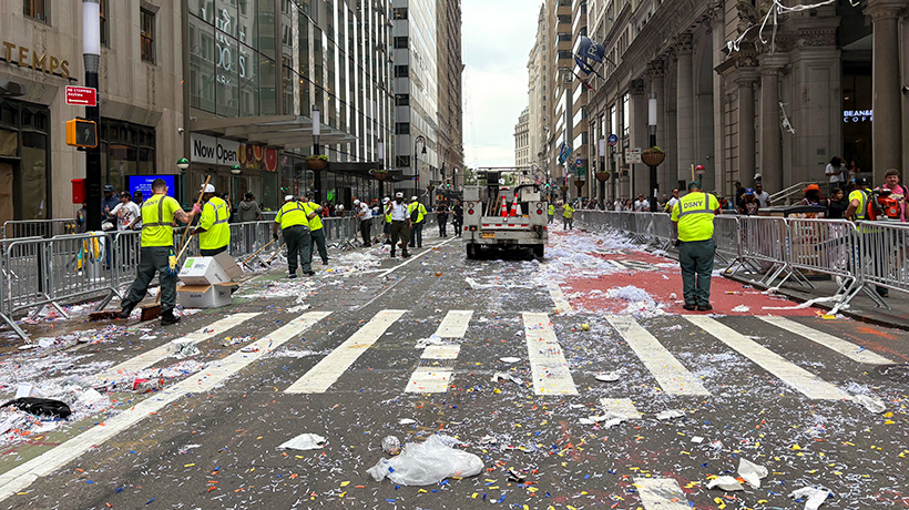 Sanitation workers sweet up confetti and trash strewn about the street after the parade
                                           