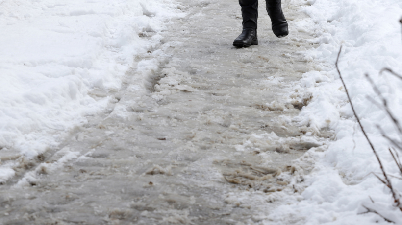 Someone's boots on a sidewalk completely covered in snow and icy
                                           