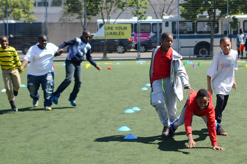 group of boys playing on field on sunny day