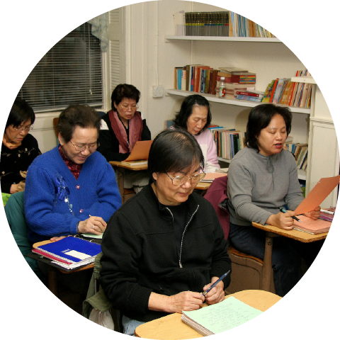 adult students sit in a classroom looking down at their desks