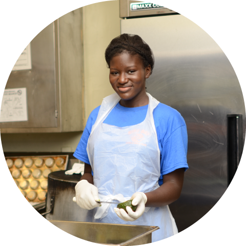 girl wearing apron in kitchen holding vegetable