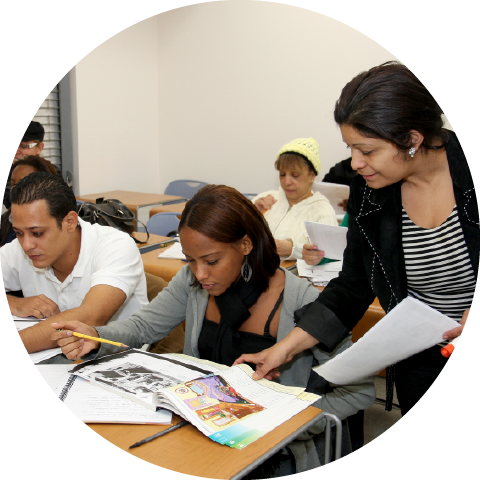 teacher looking along in book with adult students