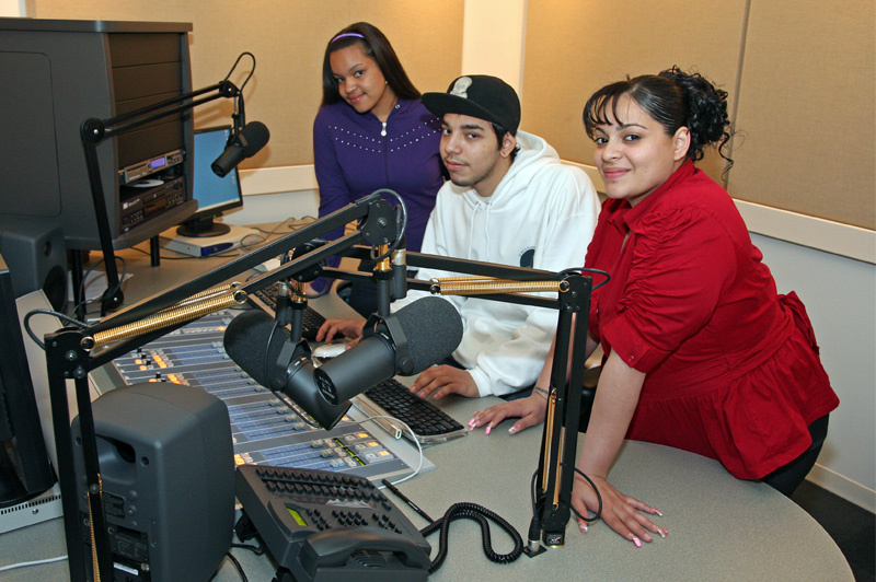 two girls and boy sitting in radio studio and posing for picture