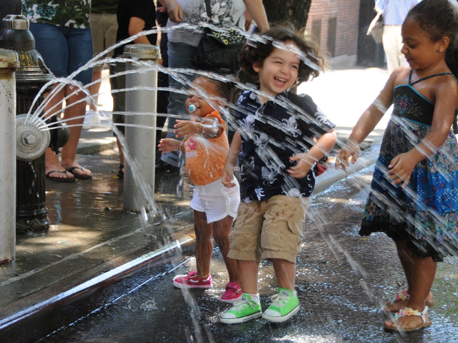 Children playing in a hydrant that has a spray cap.