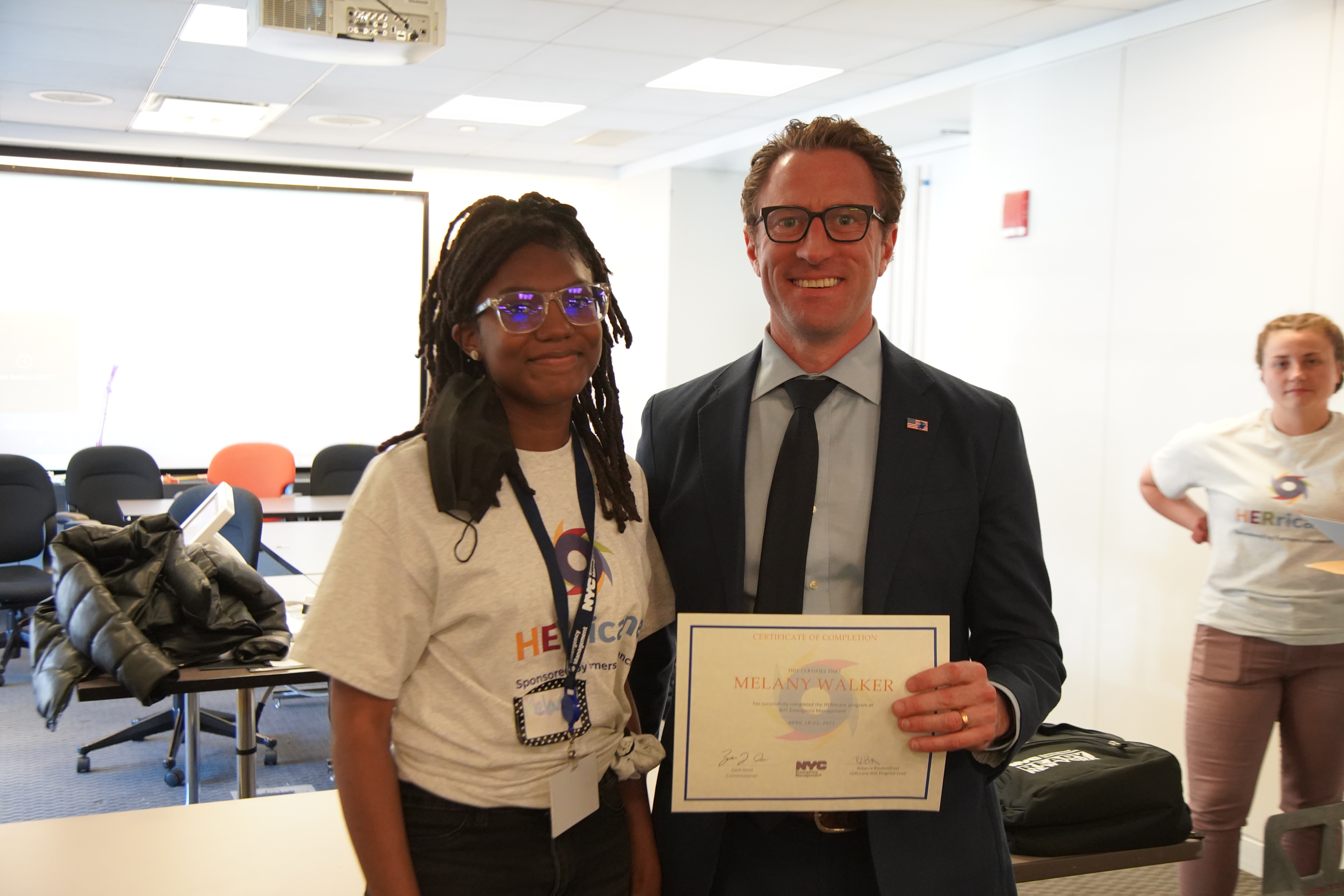 A photo of Commissioner Zach Iscol presenting a certificate of achievement/completion to a HERricane NYC program participant.